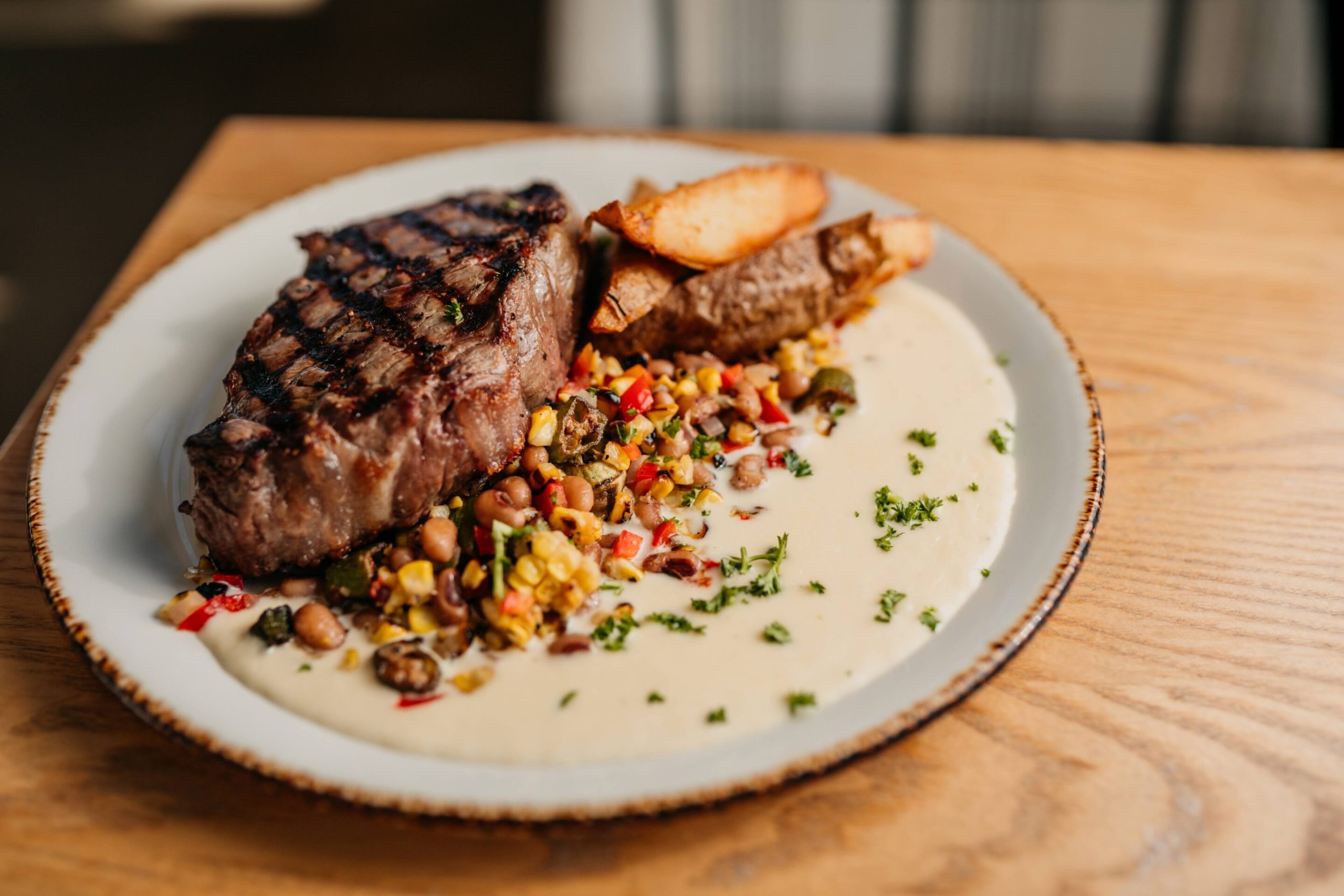 14oz New York Strip 14oz New York Strip with crisp potato wedges, succotash, corn silk beurre blanc